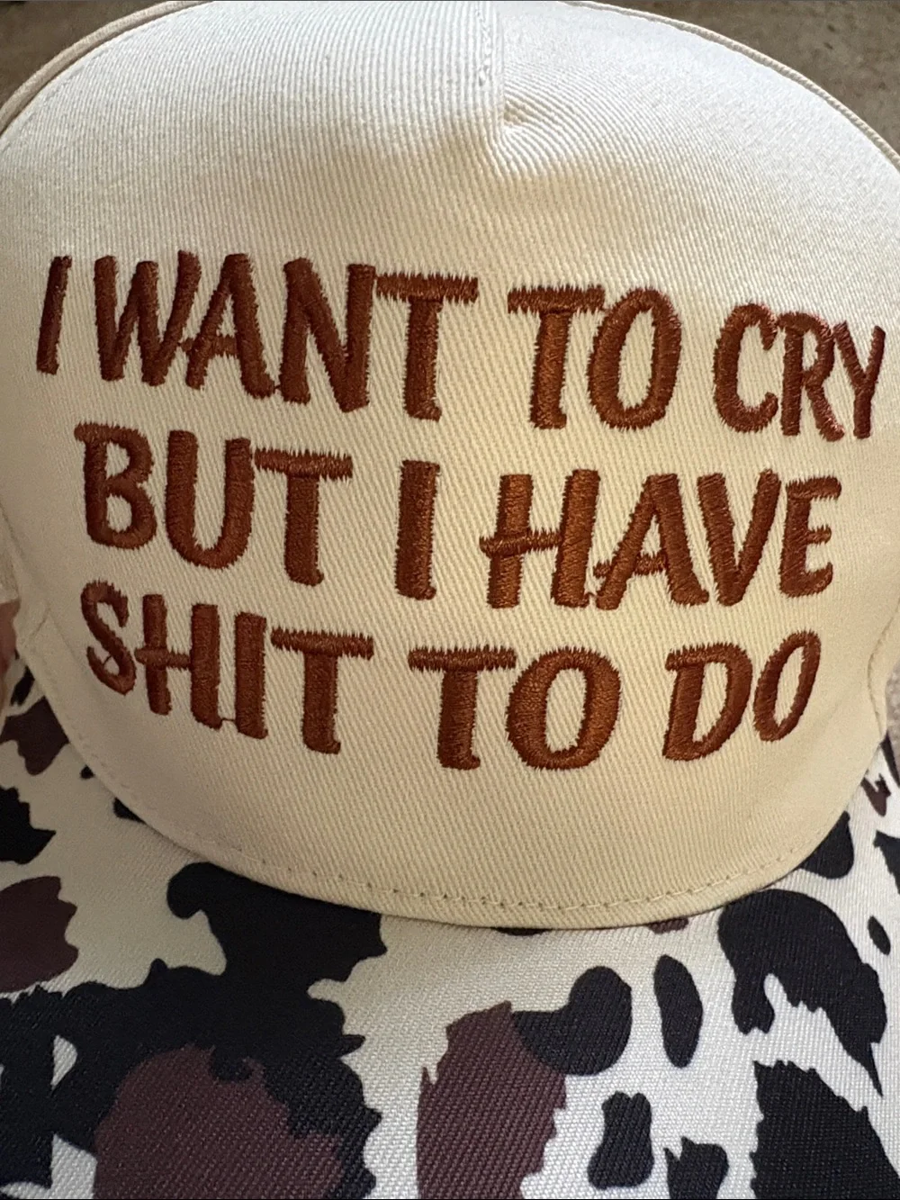 Embroiled Cream and Brown Cow Print Trucker Hat with Bold Quote